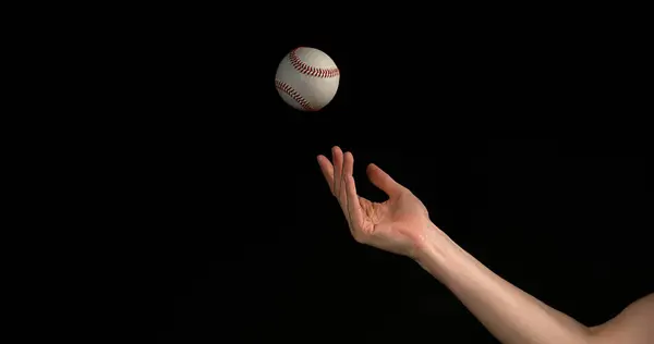 Hand of Woman Throwing a Ball of Baseball against Black Background