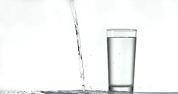 Água Sendo Derramada Vidro Contra Fundo Branco — Fotografia de Stock