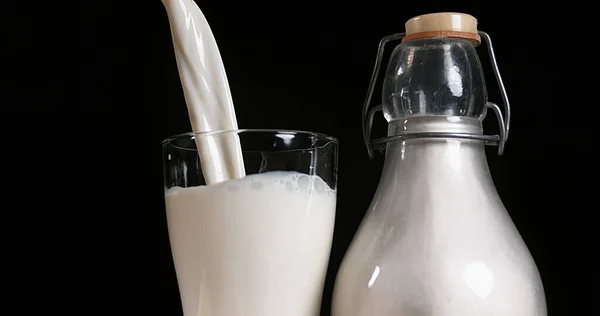 Siyah Arkaplana Karşı Bardağa Süt Dökülüyor — Stok fotoğraf