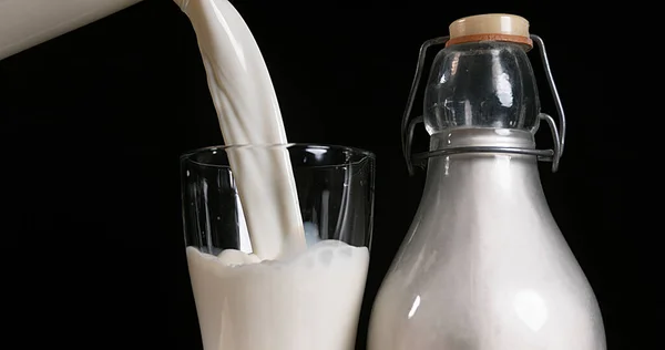 Γάλα Που Χύνεται Στο Γυαλί Κατά Μαύρο Φόντο — Φωτογραφία Αρχείου