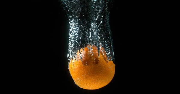 Orange, citrus sinensis, Fruit Falling into Water against Black Background