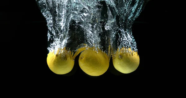 黄色柠檬 水果在黑色背景下落水 — 图库照片