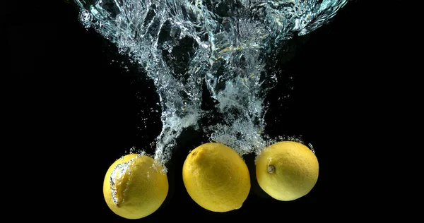 黄色柠檬 水果在黑色背景下落水 — 图库照片