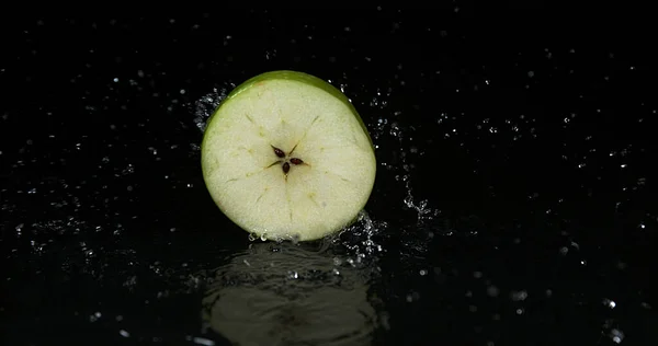 Granny Smith Apple, malus domestica, Slice turning on Water against black Background