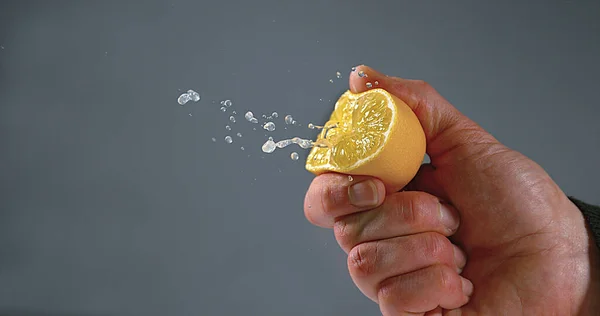 레몬을 짜내는 사람의 검은색 배경에 감귤류 — 스톡 사진