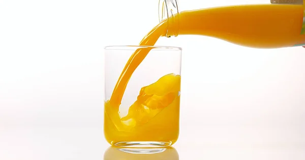 Апельсиновий Сік Будучи Виливають Склянку Білого Тлі — стокове фото