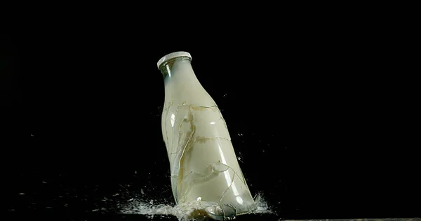 Bottle of Milk Exploding against Black Background