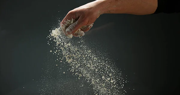 黒い背景に対する小麦粉を持つ人の手 — ストック写真