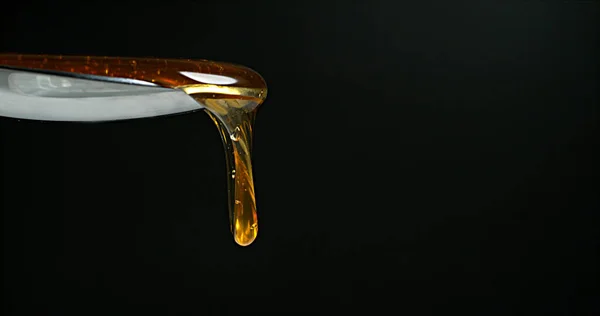 Honing Flowing Een Lepel Tegen Zwarte Achtergrond — Stockfoto