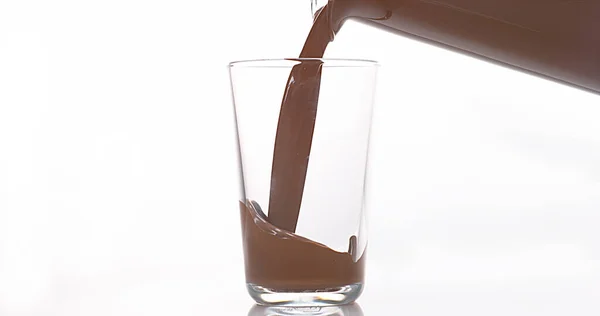 Cokelat Menuang Dalam Kaca Melawan Latar Belakang Putih — Stok Foto