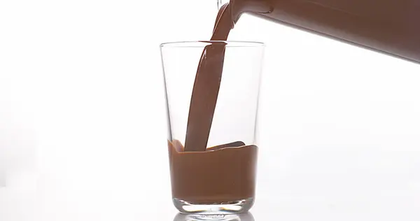 Σοκολάτα Pouring Ένα Ποτήρι Κατά Λευκό Φόντο — Φωτογραφία Αρχείου