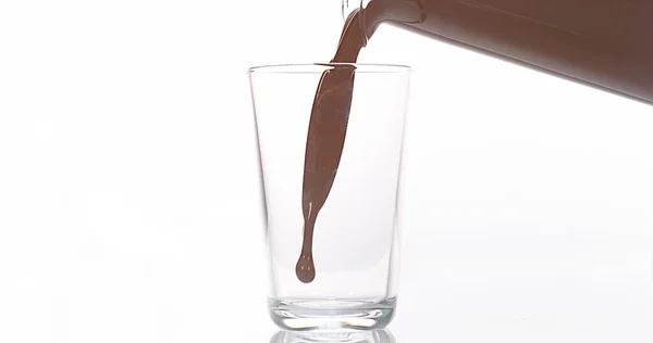 Çikolata Beyaz Arkaplan Karşı Bir Bardağa Dökülüyor — Stok fotoğraf