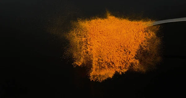 姜黄粉落在勺子上 印度香料 黑色背景 — 图库照片