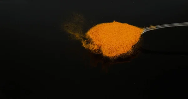 粉末落在勺子上 黑色背景 印度香料 — 图库照片
