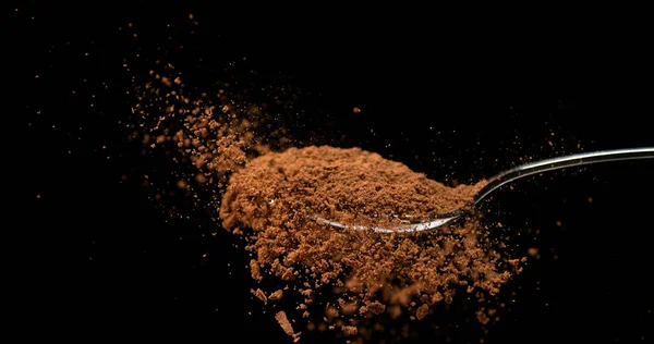 ナツメグ ミロネオの香り ブラックバックグラウンドに対するスプーンから落ちる粉 — ストック写真