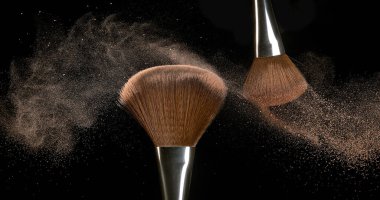 Makyaj fırçası siyah arkaplana allık tozu yayıyor