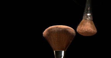 Makyaj fırçası siyah arkaplana allık tozu yayıyor
