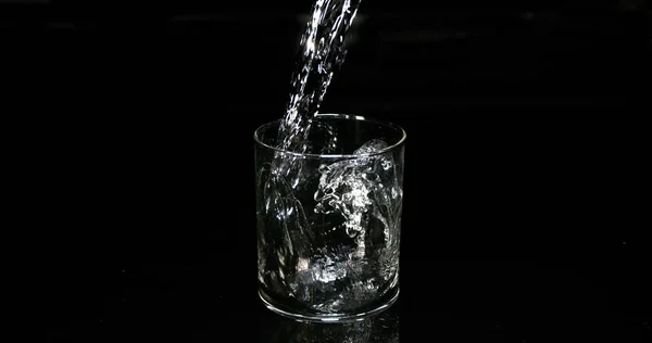 Water Dat Tegen Zwarte Achtergrond Glas Wordt Gegoten — Stockfoto