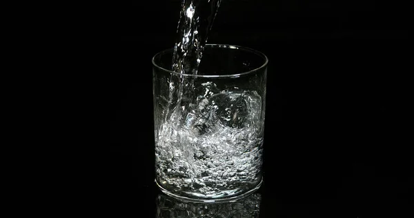 ブラックバックグラウンドにガラスに注ぐ水 — ストック写真