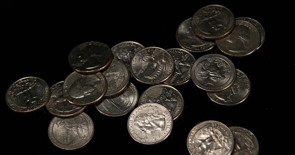 Quarter Dollar Coins Falling, Rolling and Sliding on Black Background