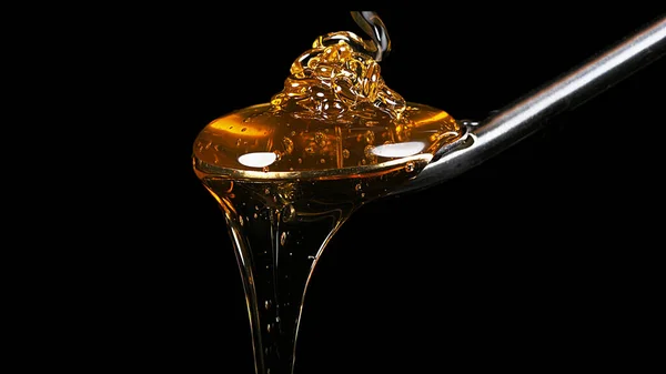 Honig Fließt Aus Dem Löffel Vor Schwarzem Hintergrund — Stockfoto