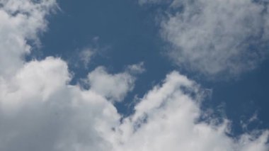Bu sahnede tüylü beyaz bulutlar canlı mavi bir gökyüzüne karşı sergileniyor, doğal projeler için mükemmel.