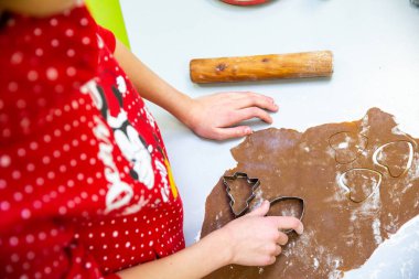 Kadın eli, tahta tahta tahta, hamurlu ve çiğ kurabiyeli fırın tepsisinin yakın fotoğrafını çek. Tahtada noel şekilli kurabiye hamuru. Tahtada Noel şekilleri olan kurabiye hamuru.