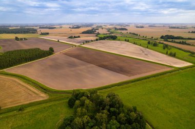 Traktör tarlası olan tarlaların havadan görünüşü. Uçsuz bucaksız tarım arazileri, toprağı süren bir traktörle tarımsal tarlaları, kırsal yolları ve çevresindeki kırsal arazileri gösteren..