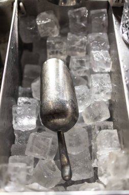 Buz Küpü Soğuk Yenileme Konsepti 'ndeki metal buz kepçesi, buzun soğuk, ferahlatıcı dokusu ve kepçenin metalik parlaklığı içecek hazırlama, barmenlik ve konukseverlik temaları için mükemmel, gevrek ve profesyonel bir atmosfer yaratır..