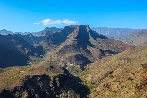 Gran Canaria 'daki engebeli dağların ve derin vadilerin göz kamaştırıcı manzarası berrak mavi gökyüzü altında, volkanik arazi ve doğal güzellik sergiliyor.. 