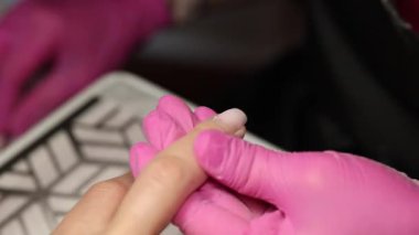 Pembe eldivenli bir tırnak makasıyla manikür yaparken tırnak makasıyla makas kesen bir tırnak teknisyeninin yakın çekimi. Yüksek kalite 4k görüntü