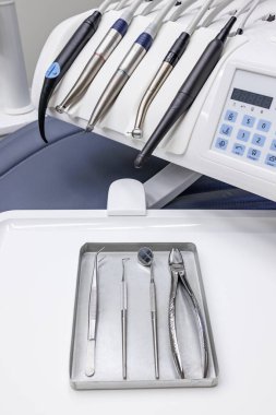 Modern bir diş kliniğinin içindeki tepsiye yerleştirilmiş el aletleri ve paslanmaz çelik aletler de dahil olmak üzere çeşitli diş aletlerinin yakın çekimi.. 