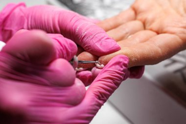 Çiviler Fransız. Pembe eldivenli profesyonel bir manikürcünün, kuafördeki tırnak derisini tırnak bakımı sırasında sökerken yüksek kaliteli bir fotoğrafı.. 