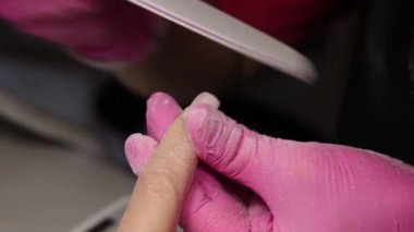 Fransız Tırnak Tarzı için dosya manikürü, tırnak matkabını kullanarak tırnakları temizleyen bir tırnak teknisyeninin yakın çekimi. Yüksek kaliteli video