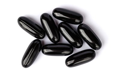 Temiz beyaz bir yüzeye dizilmiş parlak siyah softgel kapsülleri yakın plan, tipik olarak diyet takviyeleri veya ilaçlar için kullanılır. 