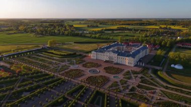 Letonya 'daki Rundale Sarayı' nın hava görüntülerinde simetrik Barok bahçeleri, tarihi mimari ve kırsal manzaralar altın saat boyunca sergilenmektedir. Yüksek kalite 4k görüntü