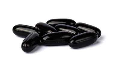 Temiz beyaz bir yüzeye dizilmiş parlak siyah softgel kapsülleri yakın plan, tipik olarak diyet takviyeleri veya ilaçlar için kullanılır. 