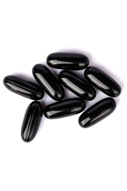 Temiz beyaz bir yüzeye dizilmiş parlak siyah softgel kapsülleri yakın plan, tipik olarak diyet takviyeleri veya ilaçlar için kullanılır. 
