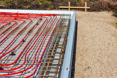 İnşaat alanındaki temel şebeke üzerine döşenmiş kırmızı borular kullanılarak zemin altı ısıtma tesislerinin kapatılması. Yüksek kalite fotoğraf