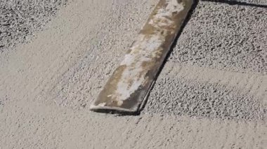 Bir inşaat işçisinin yeni dökülmüş beton zemini düzleştirmek ve düzleştirmek için uzun kulplu bir mala kullandığı yakın çekim görüntüleri. Yüksek kalite 4k görüntü