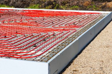 İnşaat alanındaki temel şebeke üzerine döşenmiş kırmızı borular kullanılarak zemin altı ısıtma tesislerinin kapatılması. Yüksek kalite fotoğraf