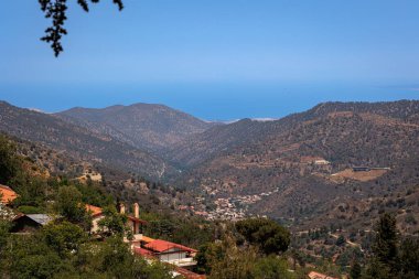 Kıbrıs Rum Kesimi 'nin yukarıdan manzaralı dağ köyü görüntüsü, tepeler ve ormanlar arasında kurulmuş bir dağ köyünün panoramik görüntüsünü gösteriyor