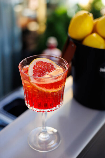 Classic Negroni cocktail served in a crystal glass with an orange slice, placed on a stylish bar counter in natural light. High quality photo