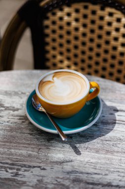 Açık bir kafede kaşıkla turkuaz bir fincan üzerinde servis edilen kremalı latte ile taze yapılmış kapuçino. Yüksek kalite fotoğraf.