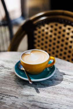 Açık bir kafede kaşıkla turkuaz bir fincan üzerinde servis edilen kremalı latte ile taze yapılmış kapuçino. Yüksek kalite fotoğraf.