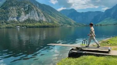 Genç bir çocuk güneşli bir günde bir dağ gölünü teftiş eder. Yüksek kalite 4k görüntü