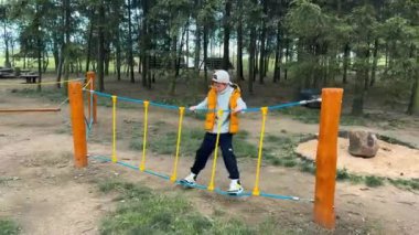 Genç bir çocuk spor sahasında ipte etkin bir şekilde yürüyor yüksek kalitede 4K görüntü.