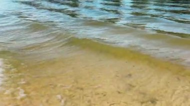 Büyüleyici sahil dalgaları berrak bir gökyüzünün altında yavaşça kıyıya vurarak sakin bir sahil manzarası yaratıyor..