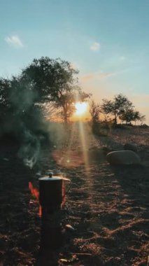 Güzel, sakin bir günbatımı manzarası. Sıcak bir kamp ateşinden yavaşça yükselen duman. Doğa aşıkları için ideal.