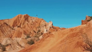 Bu nefes kesici çöl sahnesinde mavi gökyüzünün altındaki engebeli turuncu tepelerin büyüleyici güzelliğini keşfedin.